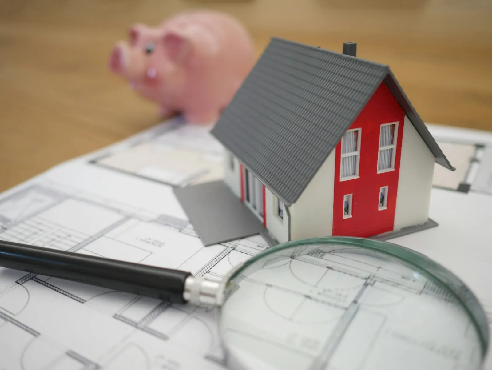 Maqueta de una casa sobre planos con una lupa